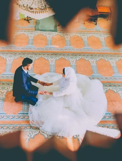 Arabic couple in a mosque holding hands during filming on their wedding day