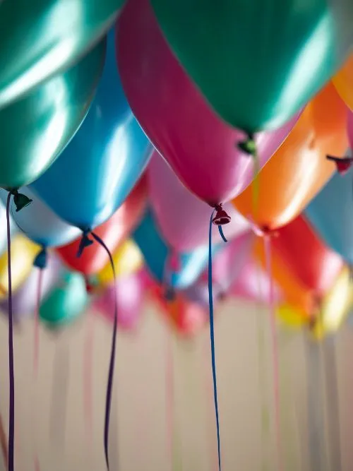 A colourful collection of birthday party balloons hanging on the ceiling