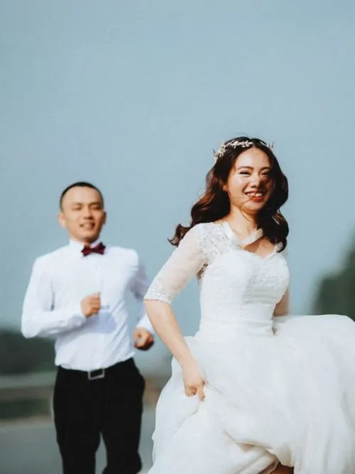 Happy looking Chinese couple be filmed outside in the sunlight on their wedding day