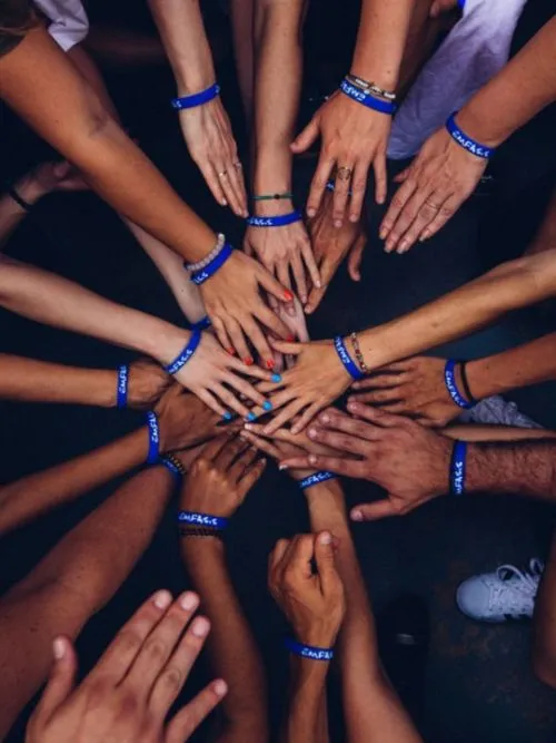 Group of charity workers putting their hands together for a team photo at an event