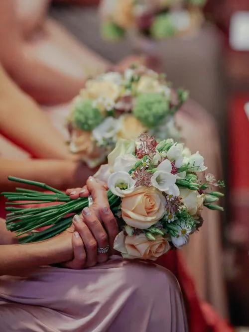 A group of bridesmaids sitting on church pews holding poses during a wedding service