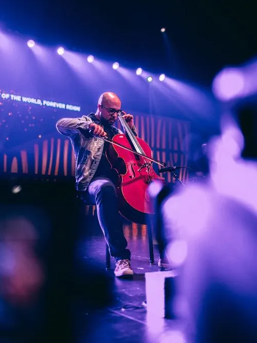 Evocative photograph of a musician on stage performing in a concert with lights behind him