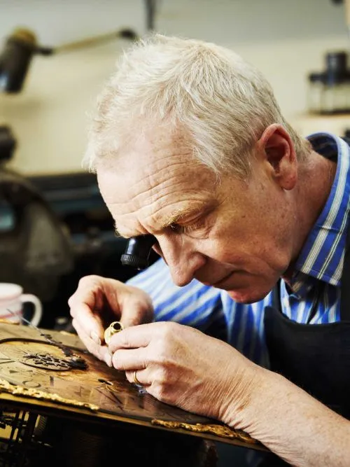 Documentary image of an experienced craftsman working on an antique clock