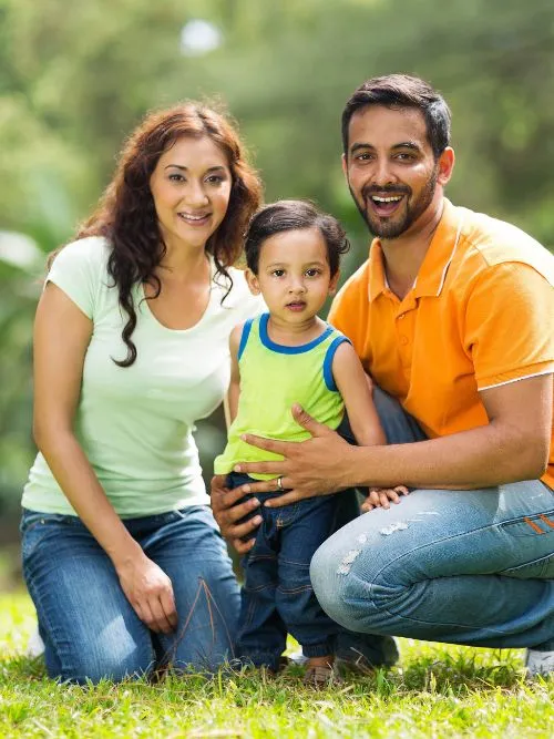 A mother and father with their young child posing for a family portrait photo outside