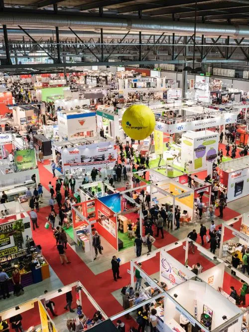 Overhead shot of a busy exhibition hall with lots of people walking around trade stands