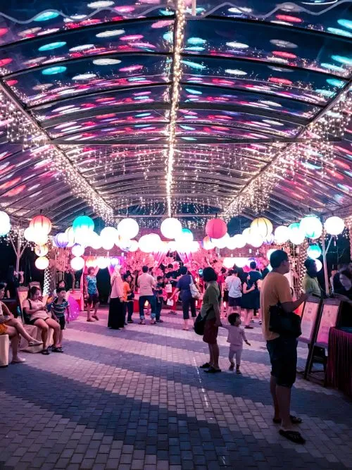 Photograph of brightly lit event with lots of people gathered for a festival or celebration