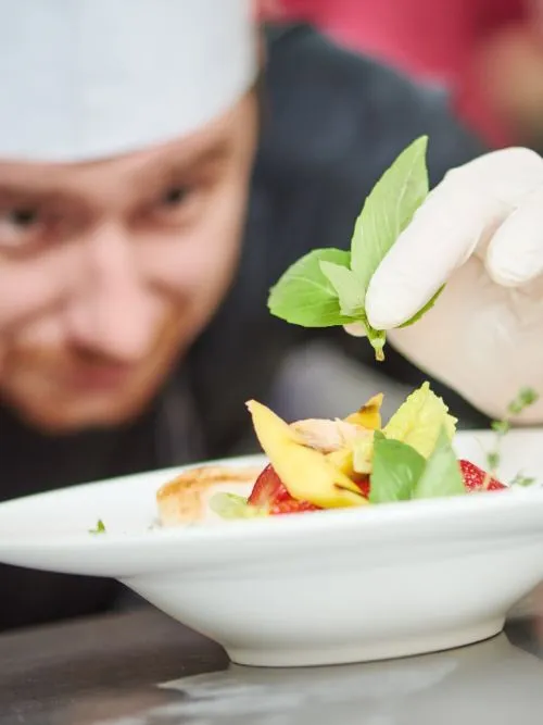 A professional chef putting the finishing touches on a dish for a cooking demonstration