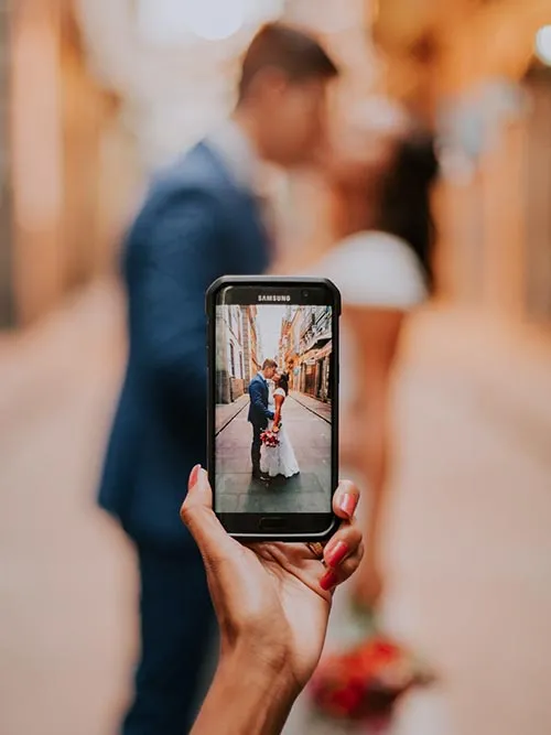 Person filming video clips of a couple using their camera phone