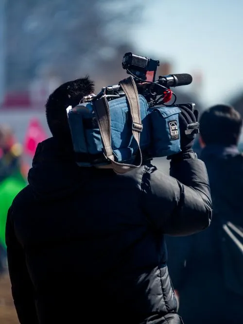 A freelance cameraman holding a Sony camera on his shoulder with a top microphone