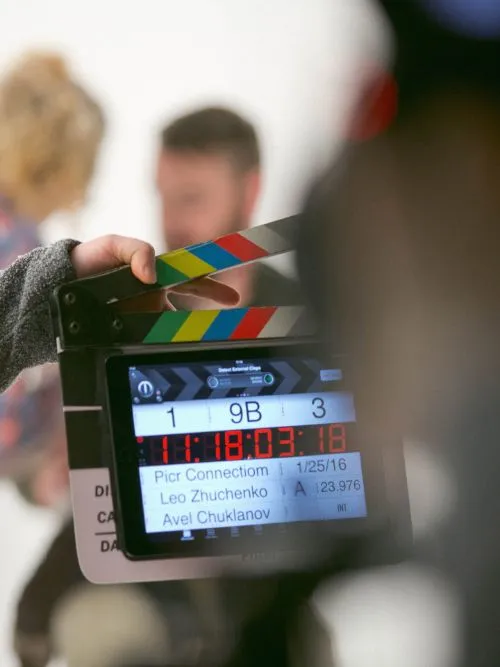 A clapper board held up in front of a scene being filmed by a freelance filmmaker