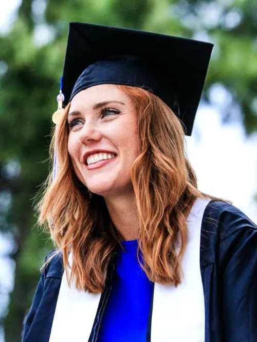 A happy looking female university graduate wearing her mortar board hat and gown