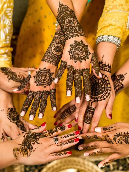 Indian bride and her bridesmaids showing their Henna tattoos to photographer during a Hindu wedding ceremony