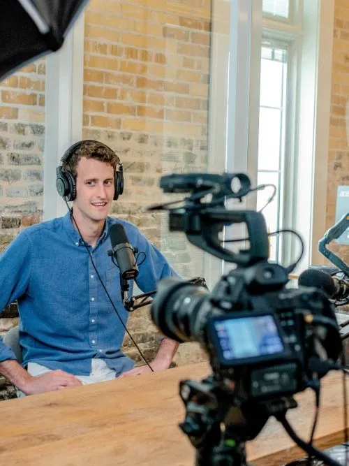 Filming of a man being interviewed in front of a Canon C100 video camera