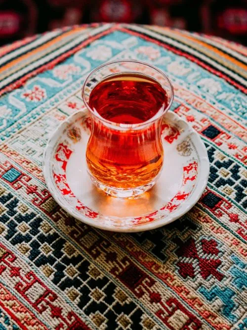 A glass of spicy Iranian chai placed on a Persian rug for a bride before her wedding