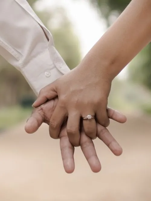 A couple holding hands and showing their engagement ring during filming of their pre-wedding video