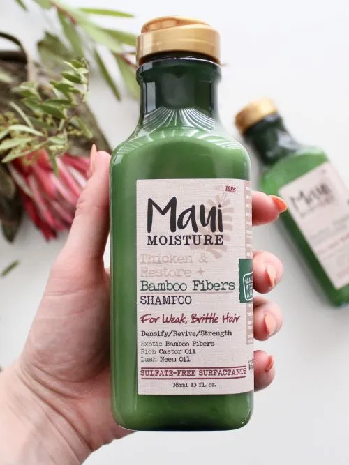 Styled image of a bottle of hair product being held in a person's hand