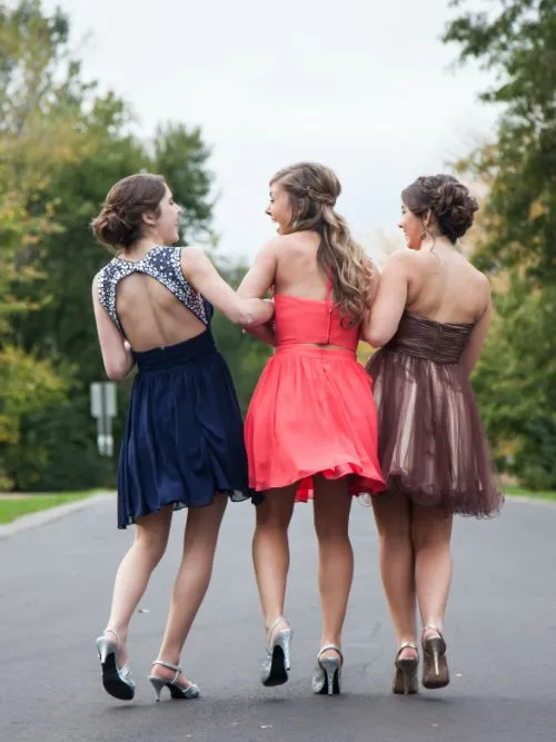 Three female students dressed up for a school prom event walking down the street