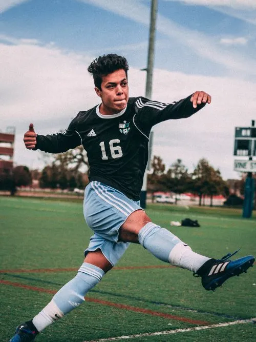 Action shot of a young man kicking the ball at a football match
