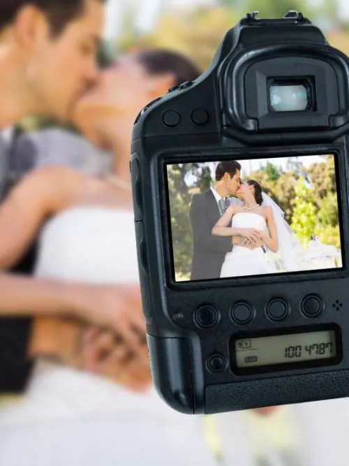Point of view of a wedding photographer capturing a bride and groom kissing on their wedding day