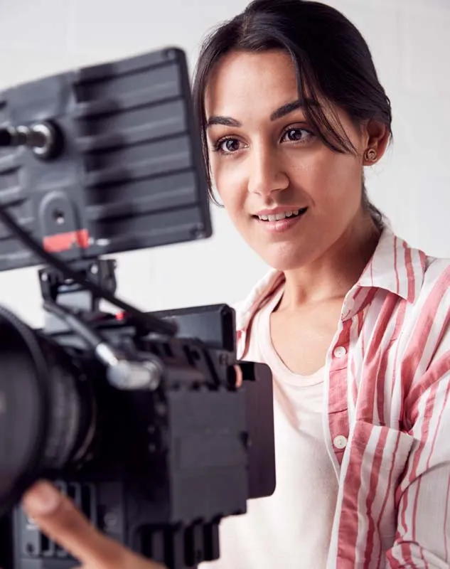 A female DBS checked videographer looking into video camera monitor