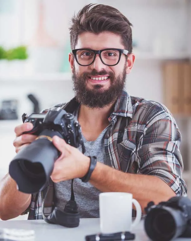 A friendly looking DBS checked photographer sat holding a camera