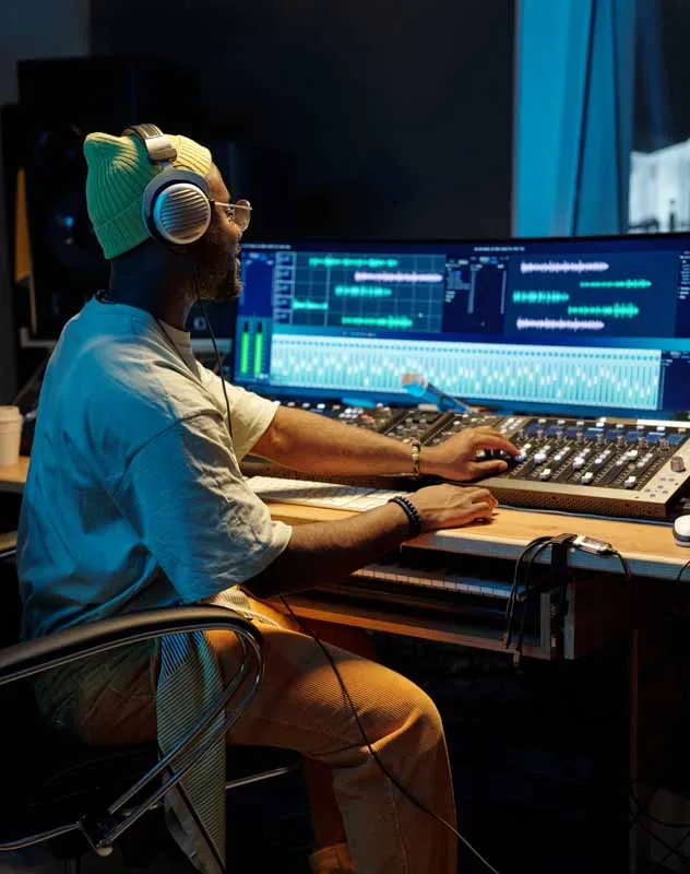 A black sound engineer sat at a mixing design in a recording studio 