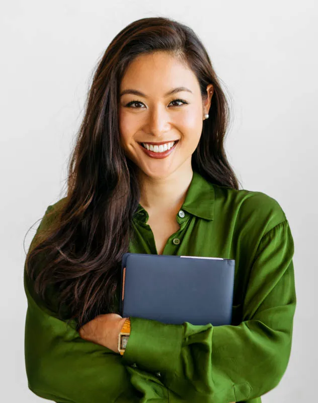 A woman in a green blouse holding a notebook posing for a corporate headshot