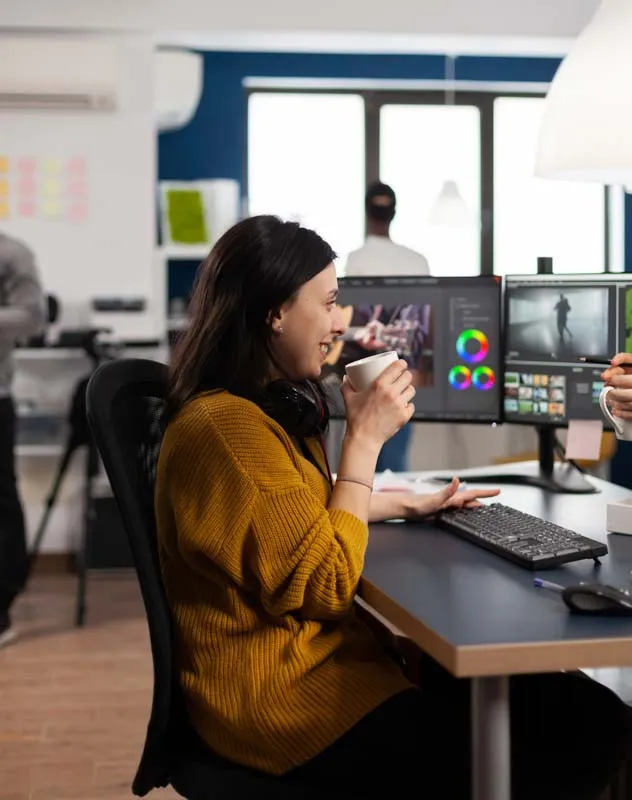 A woman sitting in an editing studio sipping coffee