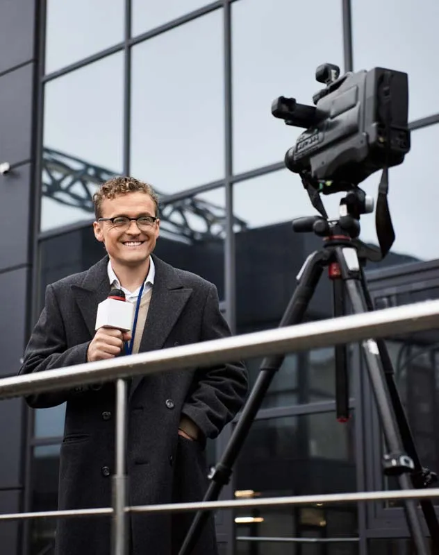 A man speaking at an event and presenting to a livestream camera