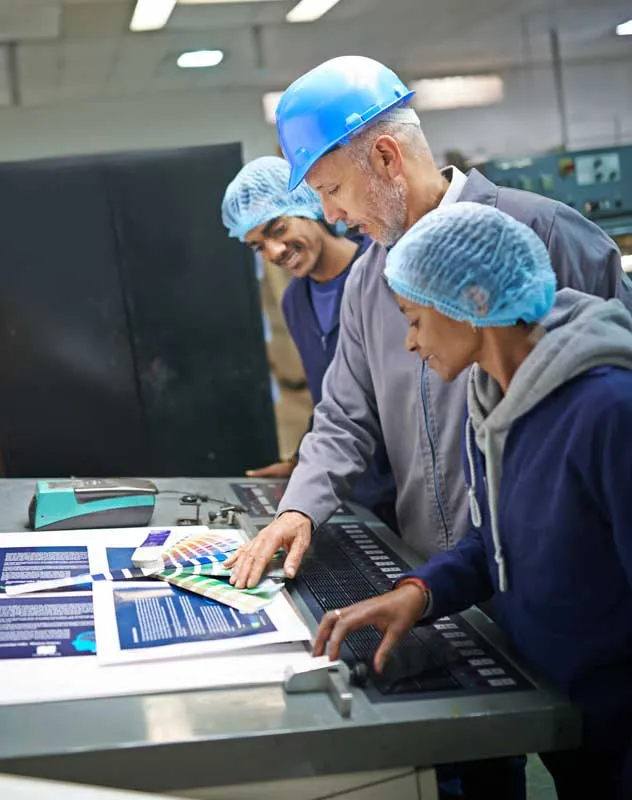 A group of three people in a factory looking at a colour swatch