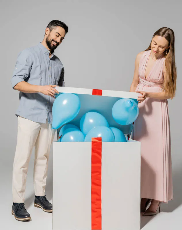 A couple revealing the gender of their child with blue balloons