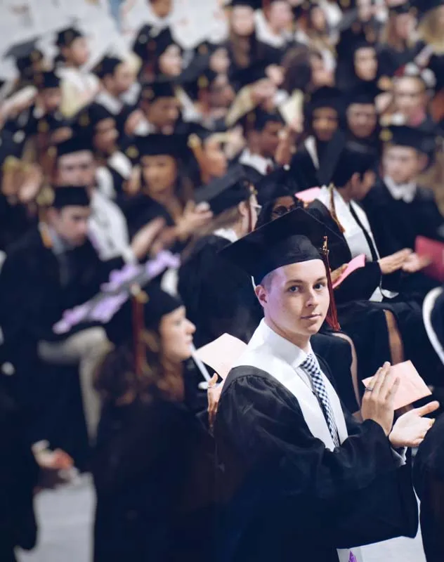 A group of students dressed on mortar board hats and gowns at a graduation ceremony