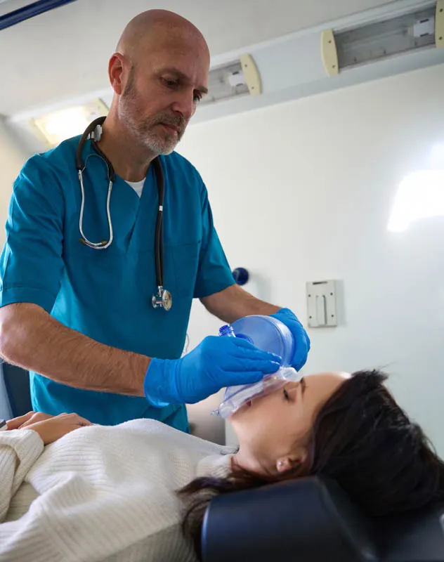 A male nurse performing gas and air treatment on a female patient in hospital