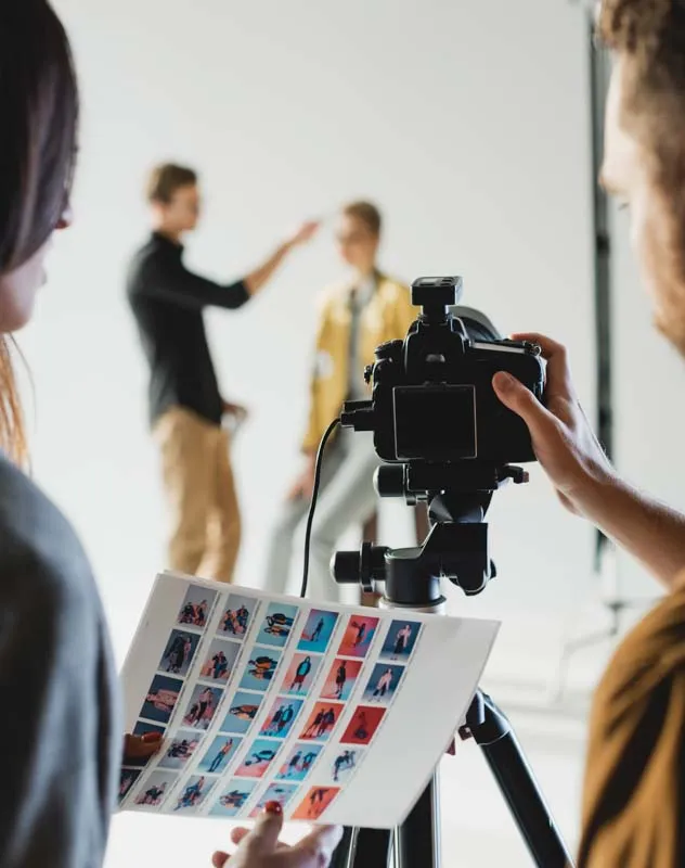 Looking between photographer and assistant at a model again white studio background