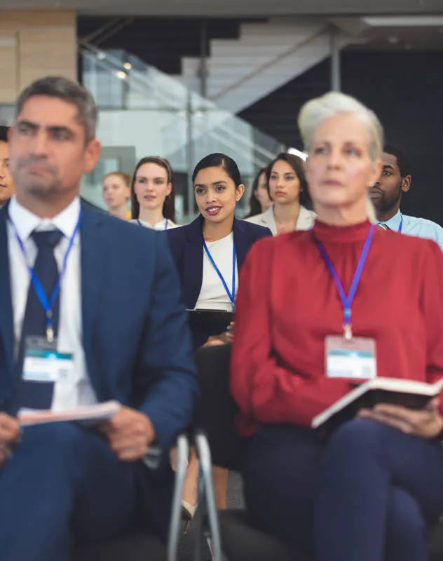 A group professionals sat listening to a seminar and taking notes