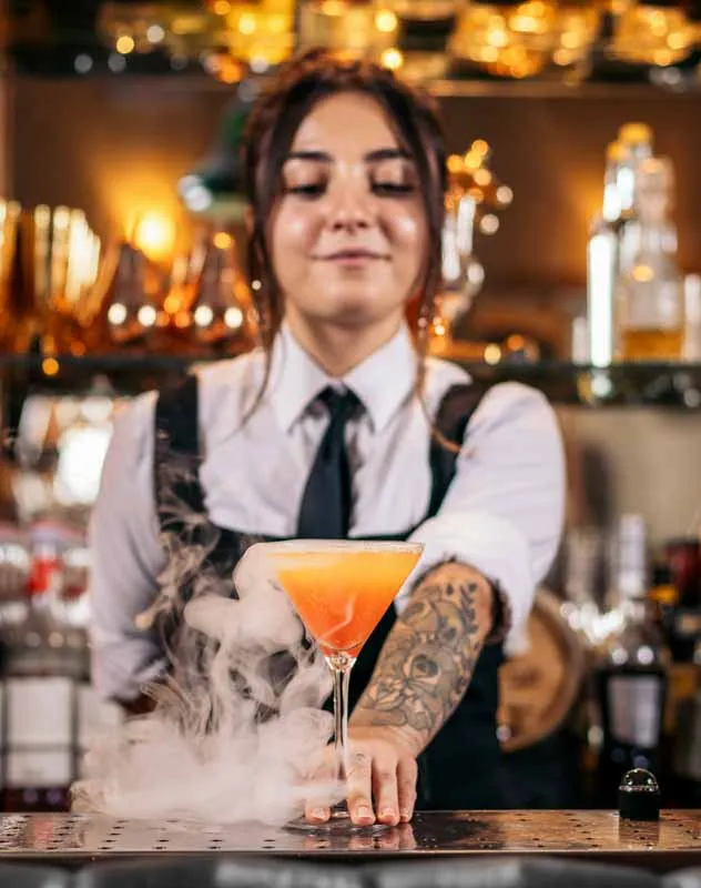 A female bar tender presenting a orange cocktail