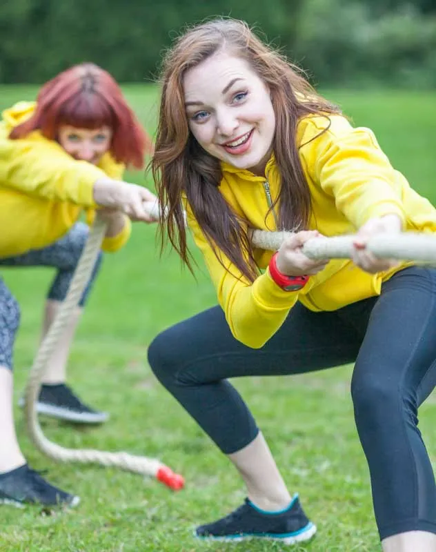 Two women in yellow shirts tugging on a rope in a competition