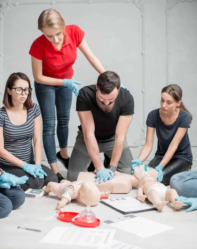 A group of men and women undertaking a first aid training exercise with a dummy