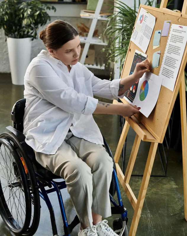 A disabled woman in a wheelchair pinning some stats to an easel