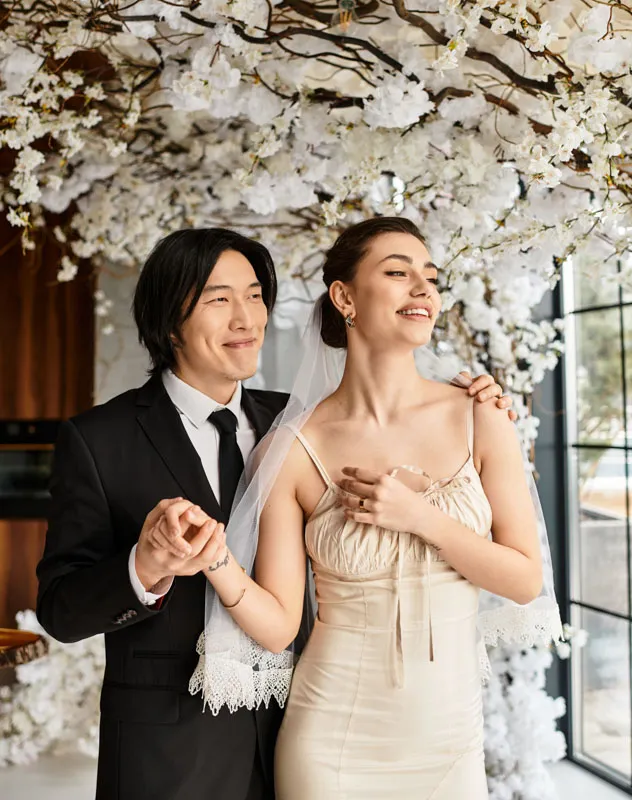 Oriental looking man and his wife standing together under a blossom on their wedding day