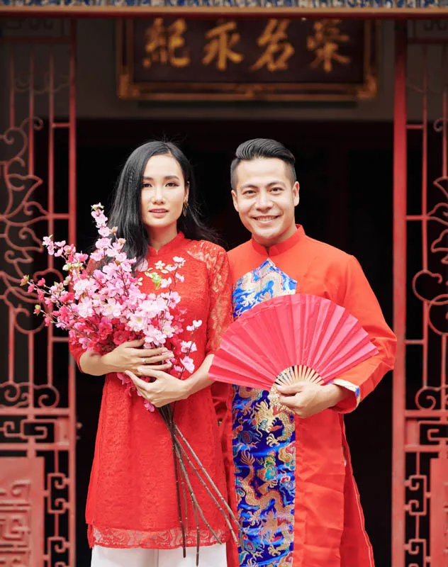 Oriental couple standing together facing photographer on their wedding day