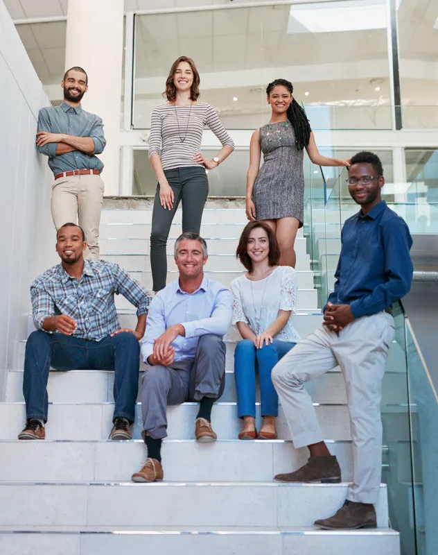 A group of employees stood together on the steps of a modern office interior