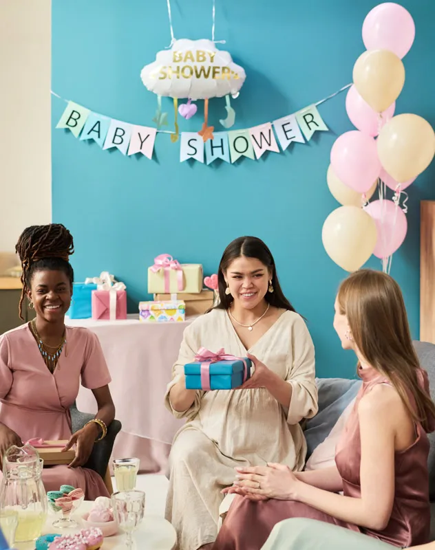 Pregnant woman sitting with two friends chatting at a baby shower