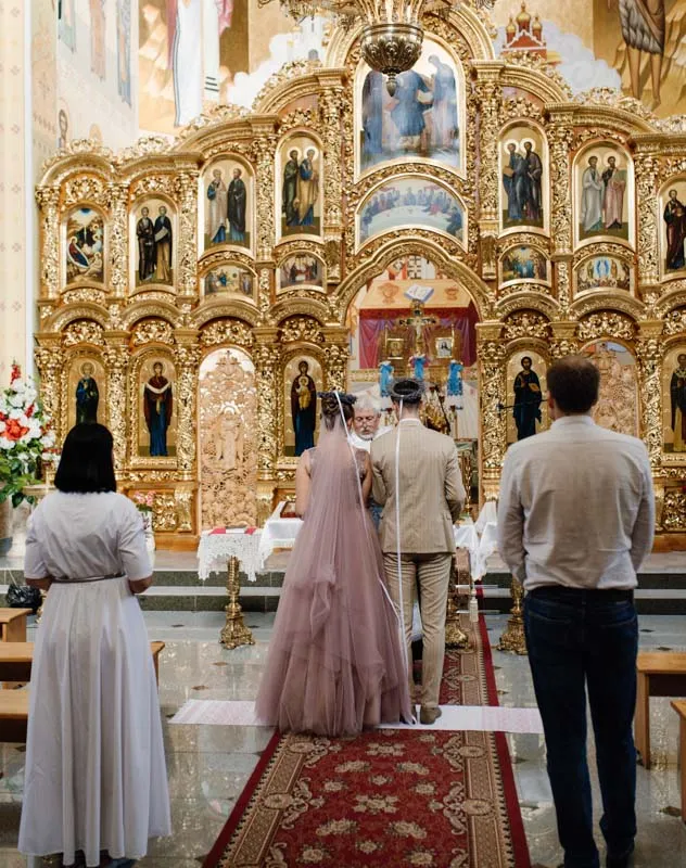 Videographer's point of view of a couple getting married in a Greek orthodox church