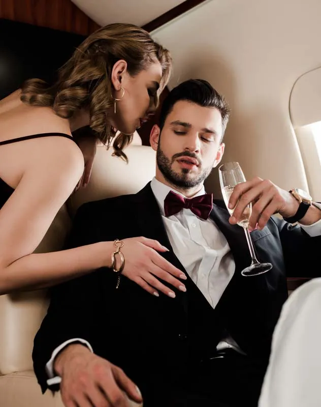 Attractive woman leaning into a man in a tuxedo on a private jet