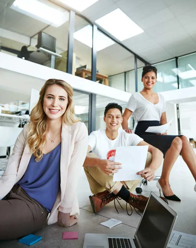 A trendy looking group of office staff sitting casually in a modern office looking at the camera