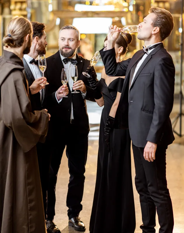 A group of well dressed people standing and chatting with champagne at a private event