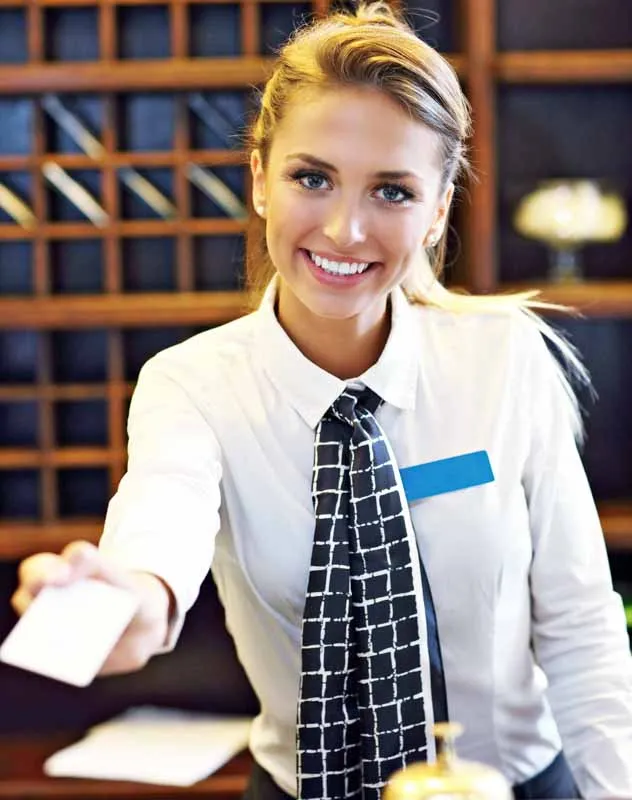 An attractive receptionist in a hotel smiling at the camera for a promotional video