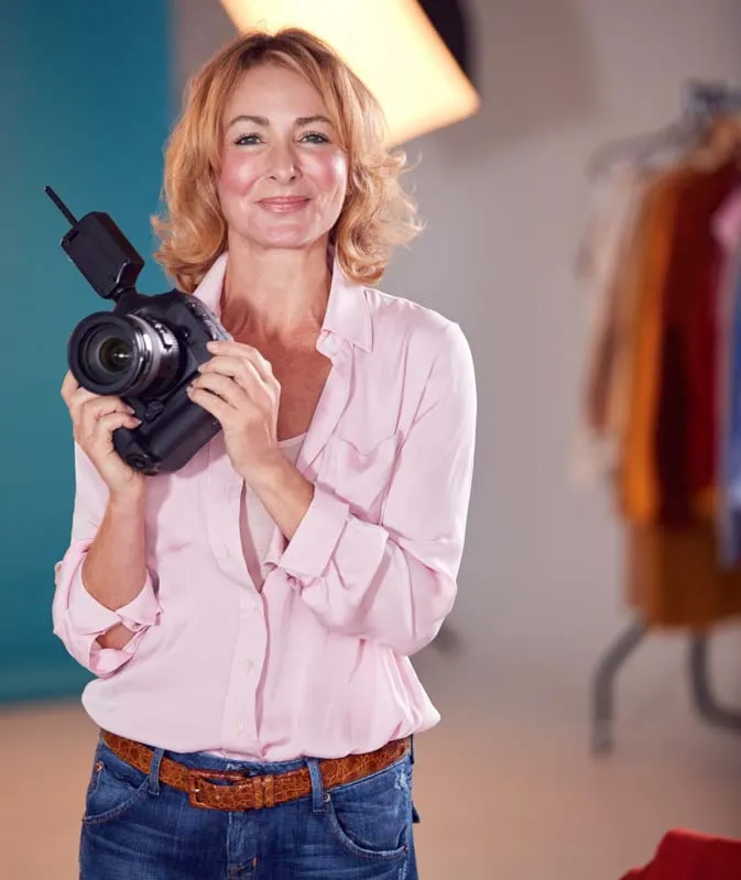A female photographer with blond hair taking a picture with a professional Canon 1D camera