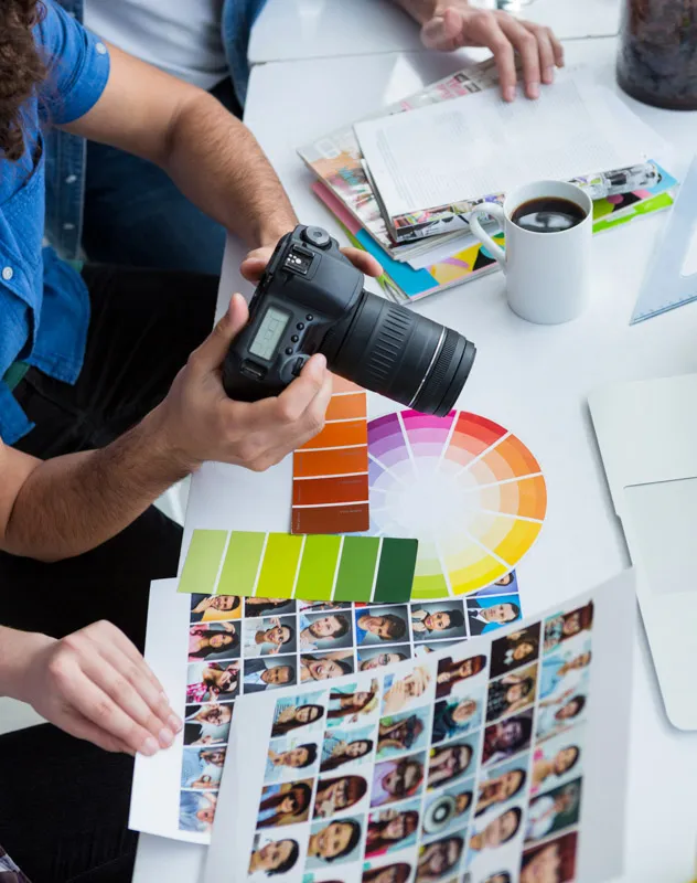 Overhead view of a photographer at their desk with a camera and contact sheets